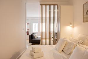 a bedroom with a white bed and a chair at Alfama Chic Penabuquel3 in Lisbon