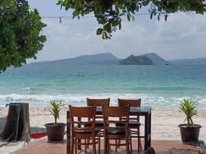 a table and chairs on a beach with the ocean at SCARLET SAILS BUNGALOW in Koh Rong Island