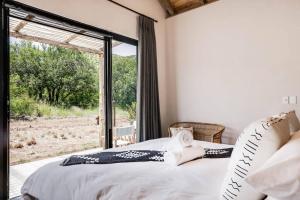 a bedroom with a bed and a large window at Makanyane Lodge in Matlhagame