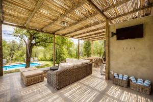 a screened in patio with a television and wicker furniture at Makanyane Lodge in Matlhagame