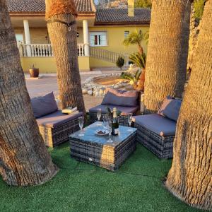 un patio con palmeras y una mesa con copas de vino en Casa Rural Familiar Piscina Sierra Balumba en Cobatillas
