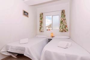 two beds in a white room with a window at On The Beach Voramar by Sealand Villas in Port de Pollensa