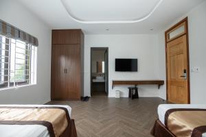 1 dormitorio con 2 camas, escritorio y TV en Nhà Nghỉ Ngọc Anh, en Nghĩa Lộ