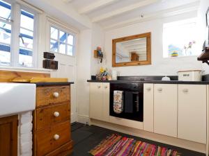 a kitchen with white cabinets and a black stove at Pass the Keys Cosy Cottage in Corris One wellbehaved dog welcome in Machynlleth