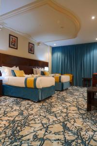 2 Betten in einem Hotelzimmer mit blauen Vorhängen in der Unterkunft Saraya Al Deafah Hotel in Mekka