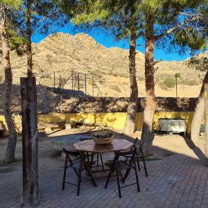 een tafel en stoelen met bomen en een speeltuin bij Casa Rural Familiar Piscina Sierra Balumba in Cobatillas