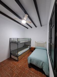 Casa Rural Alberquillas في لا بويبلا دي لوس إينفانتيس: غرفة نوم بسريرين بطابقين ومروحة سقف