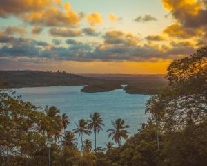 uma vista para um rio com palmeiras e um pôr-do-sol em Villa Velha Flats em Itamaracá