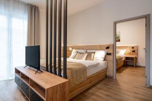 Schlafzimmer mit einem Bett, einem TV und einem Spiegel in der Unterkunft Resort Aurum Residence A in Černý Důl