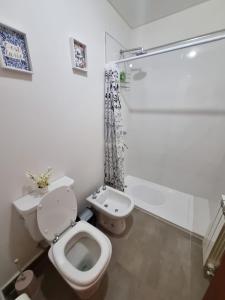 y baño blanco con aseo y ducha. en UMA en Salta