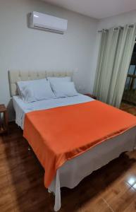 una camera da letto con un letto con una coperta arancione sopra di Vila Taipu a Barra Grande