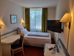 a hotel room with a bed and a desk and a television at myMINGA13 - Hotel & serviced Apartments in Munich