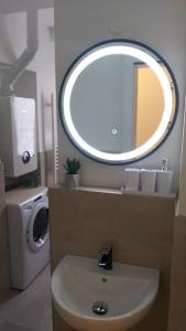 a bathroom with a sink and a round mirror at White brick Apartment in Zagreb