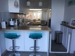 uma cozinha com dois bancos azuis num balcão em Luxurious & modern on-the-beach family retreat em Boulmer
