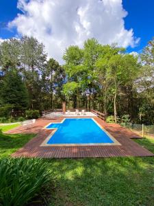 a swimming pool in a yard with a wooden deck at Pousada O Cantinho da Raposa in Monte Verde