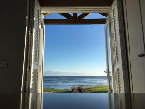 an open door with a view of the ocean at Luxurious & modern on-the-beach family retreat in Boulmer