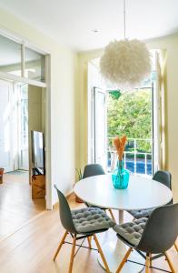 une salle à manger avec une table et des chaises blanches dans l'établissement Casa St Yves - Sunny flat in Setúbal on Av Luisa Todi, à Setúbal