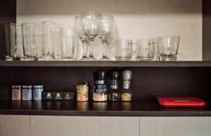 a shelf with wine glasses and bottles on it at Ultracentral Ploiesti Apartment-Free Private Parking in Ploieşti
