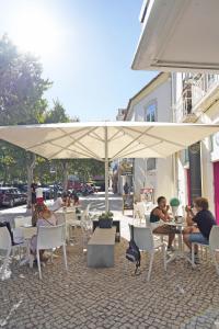 un gruppo di persone seduti ai tavoli sotto un ombrello di Casa St Yves - Sunny flat in Setúbal on Av Luisa Todi a Setúbal