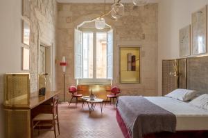 a bedroom with a bed and a desk and chairs at Palazzo Luce in Lecce