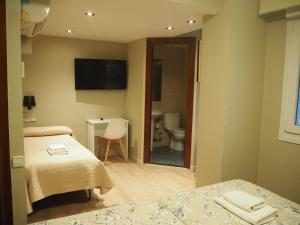 a room with two beds and a bathroom with a toilet at Hostal Acella in Pamplona