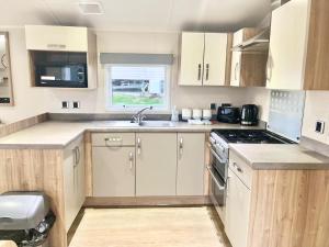 a kitchen with white cabinets and a sink and a stove at Our Lodge at Newquay Bay NB35 in Newquay