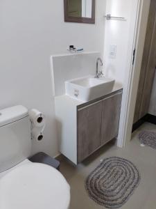 Baño blanco con lavabo y aseo en Apartamento Locação Temporada em Foz do Iguaçu, en Foz do Iguaçu