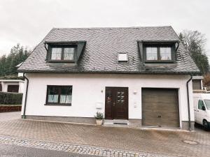 une maison blanche avec deux fenêtres et un garage dans l'établissement Ferienwohnung zum Schreckenberg, à Annaberg-Buchholz