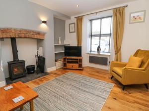 a living room with a fireplace and a chair and a television at Bryants Cottage in Chulmleigh