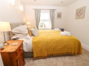 a bedroom with a bed with a yellow blanket and a window at Bryants Cottage in Chulmleigh