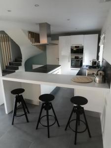 - une cuisine avec un comptoir blanc et des tabourets dans l'établissement Villa 8 personnes à proximité des bords de Saône, à Montmerle Sur Saône