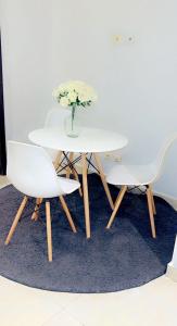 a white table with two chairs and a vase of flowers at Sweet home in Dakar