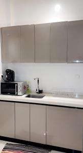 a white kitchen with a sink and a microwave at Sweet home in Dakar