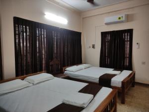 a room with two beds and a window at Sreevalsam Guest House in Trivandrum