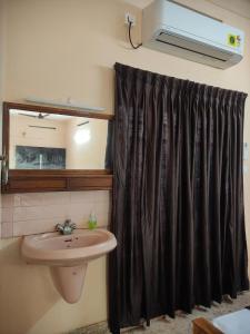 a bathroom with a sink and a black shower curtain at Sreevalsam Guest House in Trivandrum