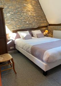 a bedroom with a large bed and a stone wall at Hostellerie Du Chateau in Châteauneuf