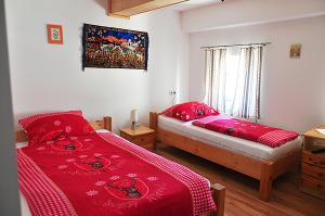 1 Schlafzimmer mit 2 Betten mit roter Bettwäsche und einem Fenster in der Unterkunft Mostheuriger Steyrdurchbruchalm in Leonstein