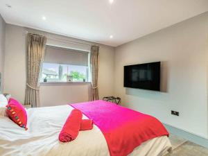 una camera con letto, cuscini rosa e TV di Mya Cottage a Wilpshire