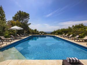 a large swimming pool with chairs and an umbrella at Villa Quinta Marinha - 9 bedroom villa 20 guests stunning location overlooking sea huge private p in Lagoa
