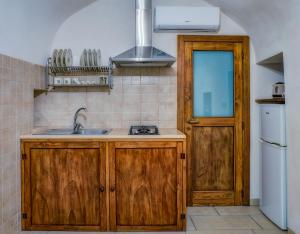 cocina con armarios de madera, fregadero y nevera en Il Trulletto en Montalbano