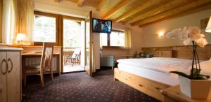 - une chambre avec un lit, un bureau et une table dans l'établissement Hotel Pinei, à Ortisei