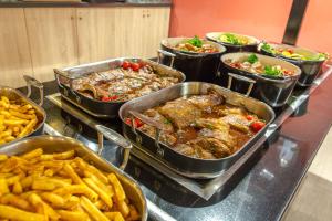 un buffet con diversi piatti e patatine fritte di SOWELL RESIDENCES Les Lauriers Roses a Cap d'Agde