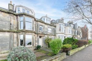 an old stone house with white windows and bushes at Spectacular Penthouse , 100 yds to Old Course , Balcony in St. Andrews