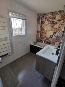 ein Bad mit einem weißen Waschbecken und einem Fenster in der Unterkunft Villa 8 personnes à proximité des bords de Saône in Montmerle Sur Saône