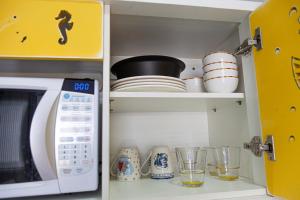 a kitchen with a microwave and plates and glasses at Pousada Guaricana in Pontal do Paraná