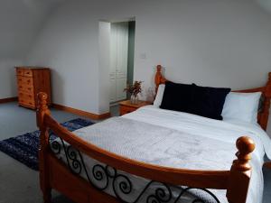 1 dormitorio con cama de madera con sábanas blancas en Skye's Atlantic Retreat, en Miltown Malbay