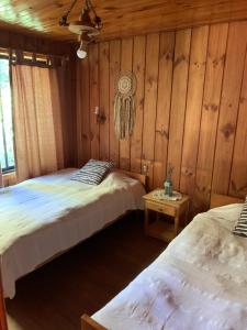 two twin beds in a room with wooden walls at Cabaña Pucón in Pucón
