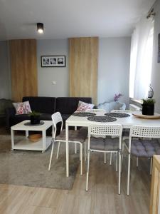 - un salon avec une table et des chaises blanches dans l'établissement Domki U Skrzata, à Łeba