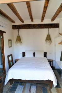 een slaapkamer met een wit bed en houten plafonds bij Romantico Apartamento en el Puerto de Denia in Denia