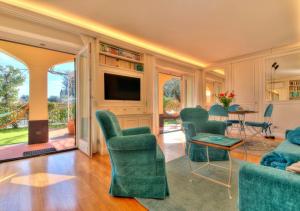 a living room with green chairs and a television at Villa Mares - sea view, free garage in Rapallo